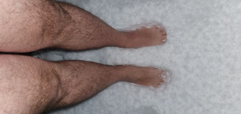 Ein paar nackte Füße stehen im Schnee